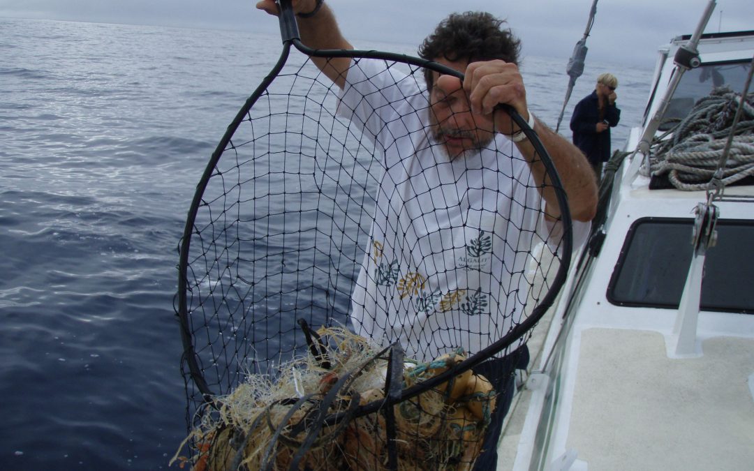 Captain holds up a big net with a ghost net inside it