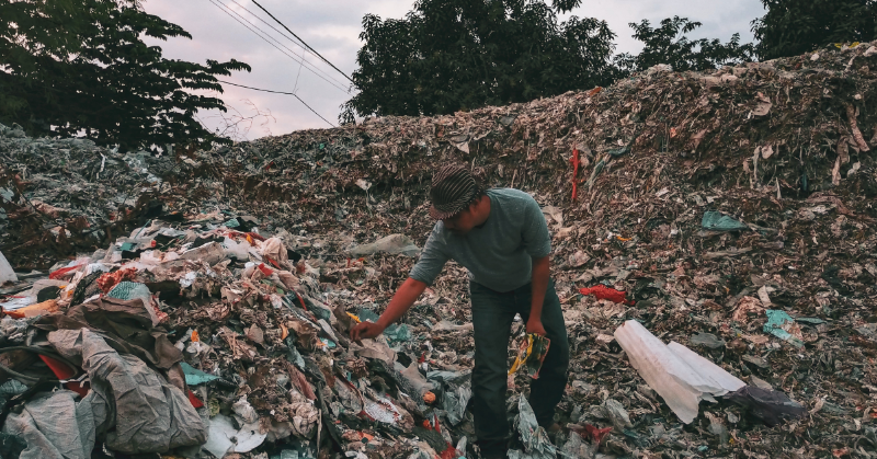 Project image card - shows a person investigating head-high piles of plastic waste.