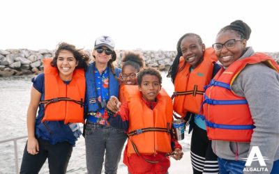 Students and educators wearing lifevests pose for a photo on the bow of a boat