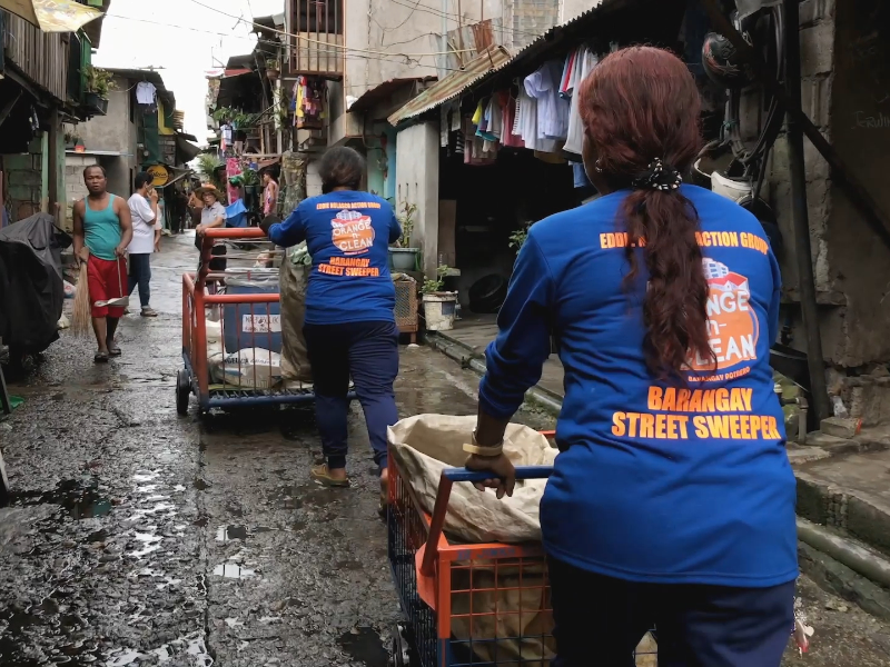 Informal waste pickers in Manila walk down a street to collect and sort waste.