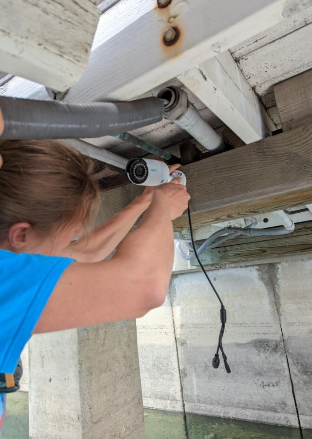 Person installing a camera under a dock.