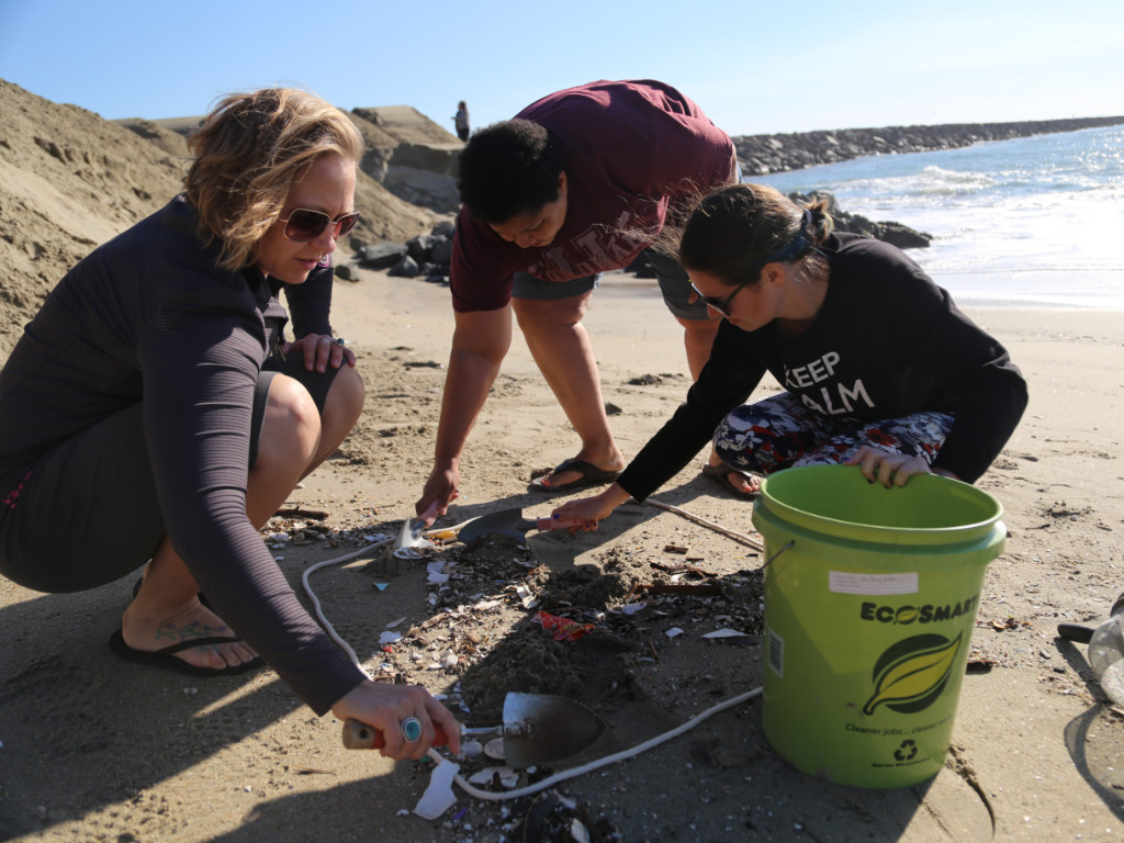 Three people collecting a sand sample on a beach.