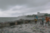 Workers sweep plastic debris washing over seawall