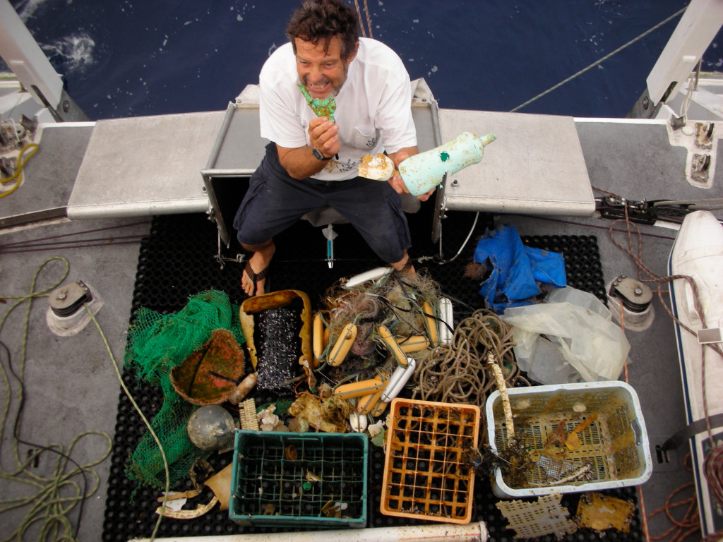 Captain Moore on the deck of his catamaran sitting surrounded by plastic debris pulled from the ocean