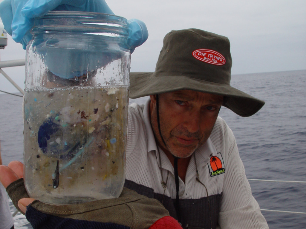 Captain Moore holds up a jar containing an ocean water sample with microplastics