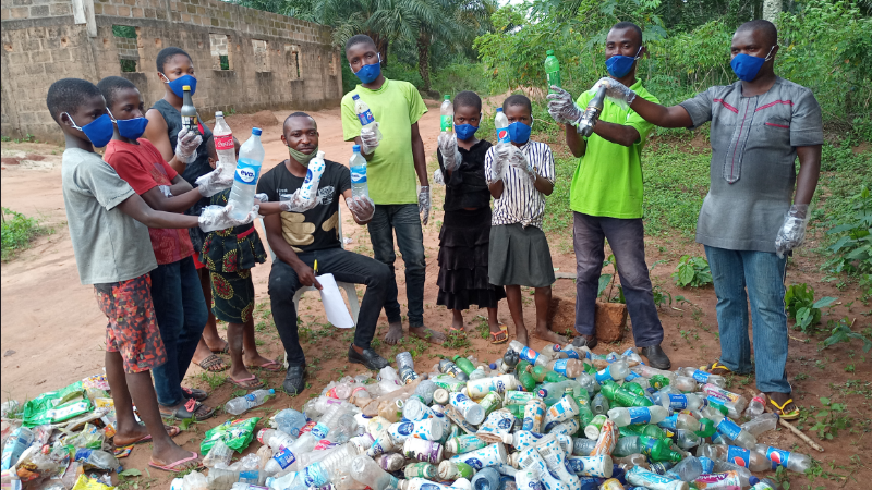 Educator Ezeigwe of Preventing Marine Plastic Pollution in Nigeria, and his students pose with collected plastic water bottles.