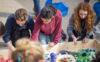 3 students work on a plastic debris mural