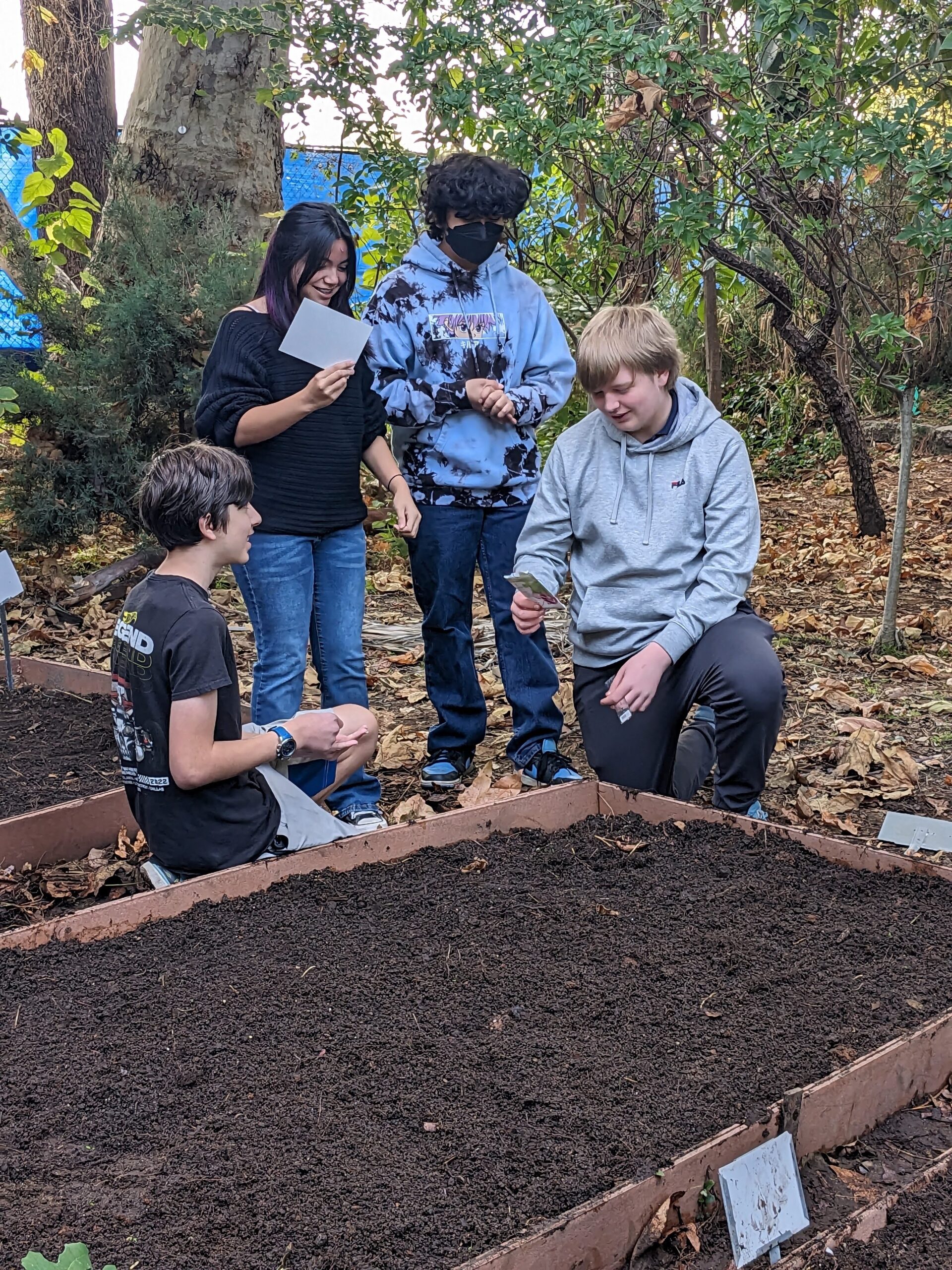 students planting seeds in a raised bed at their school garden