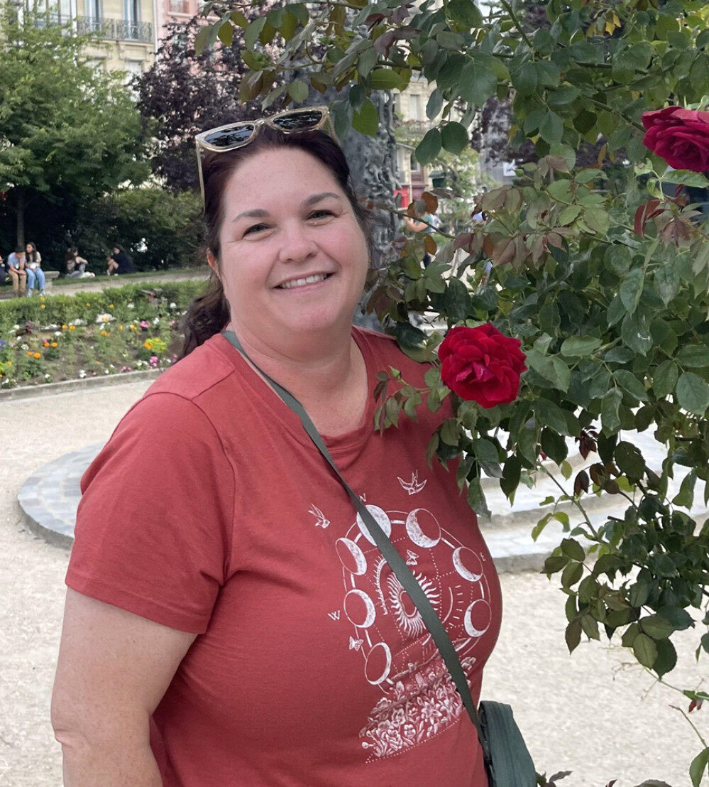 Environmental Educator Pam Rydzisnki in front of a rose bush