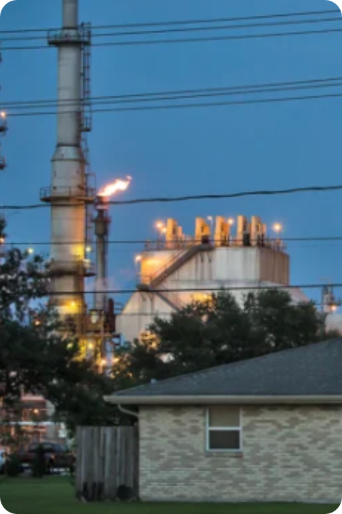 Image card - click to go to the Breathe This Air video. Image shows a home in front of a refinery.