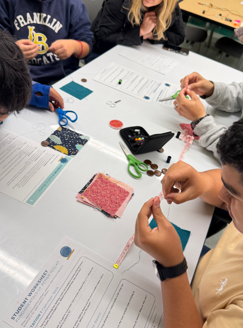 Students learning to sew on a button.